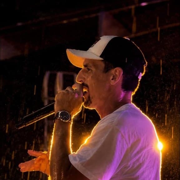 A performer on stage holding a microphone under purple and gold light