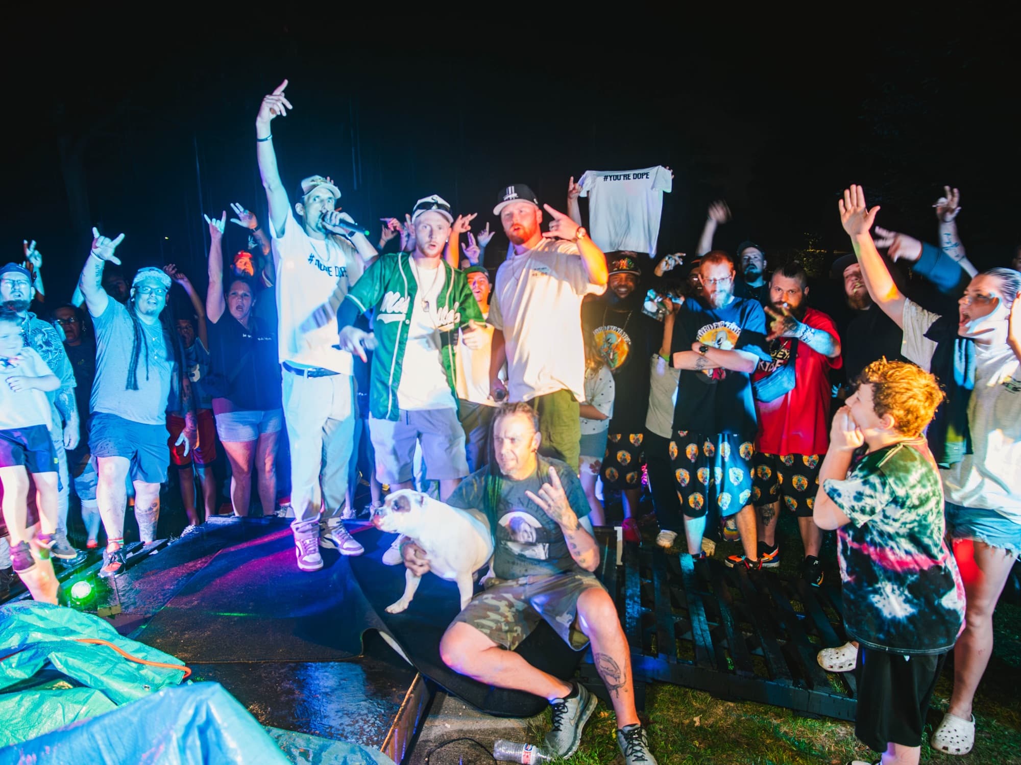 A night-show crowd with a YOU’RE DOPE shirt held up